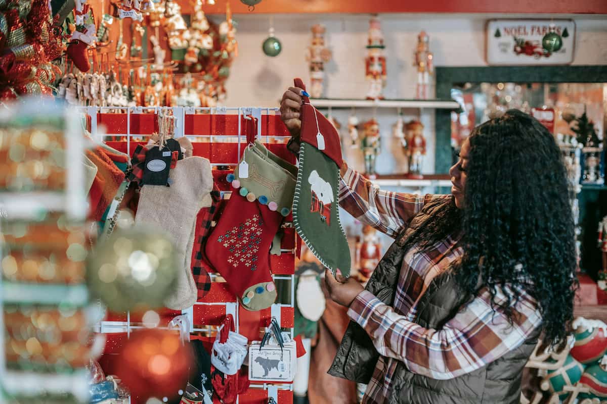 Fotografia de uma mulher olhando para enfeites de natal que estão sendo vendidos em uma loja.