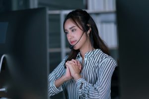Mulher usando headset, trabalhando em um ambiente de escritório, concentrada em um computador.