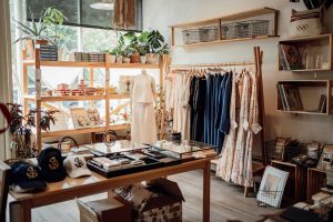 Espa&ccedil;o comercial dedicado a vestu&aacute;rio, exibindo roupas e acess&oacute;rios variados, simbolizando nomes para lojas de roupas.