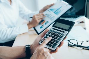 Profissionais analisando gr&aacute;ficos e calculadora para avaliar o risco de cr&eacute;dito em uma reuni&atilde;o financeira.