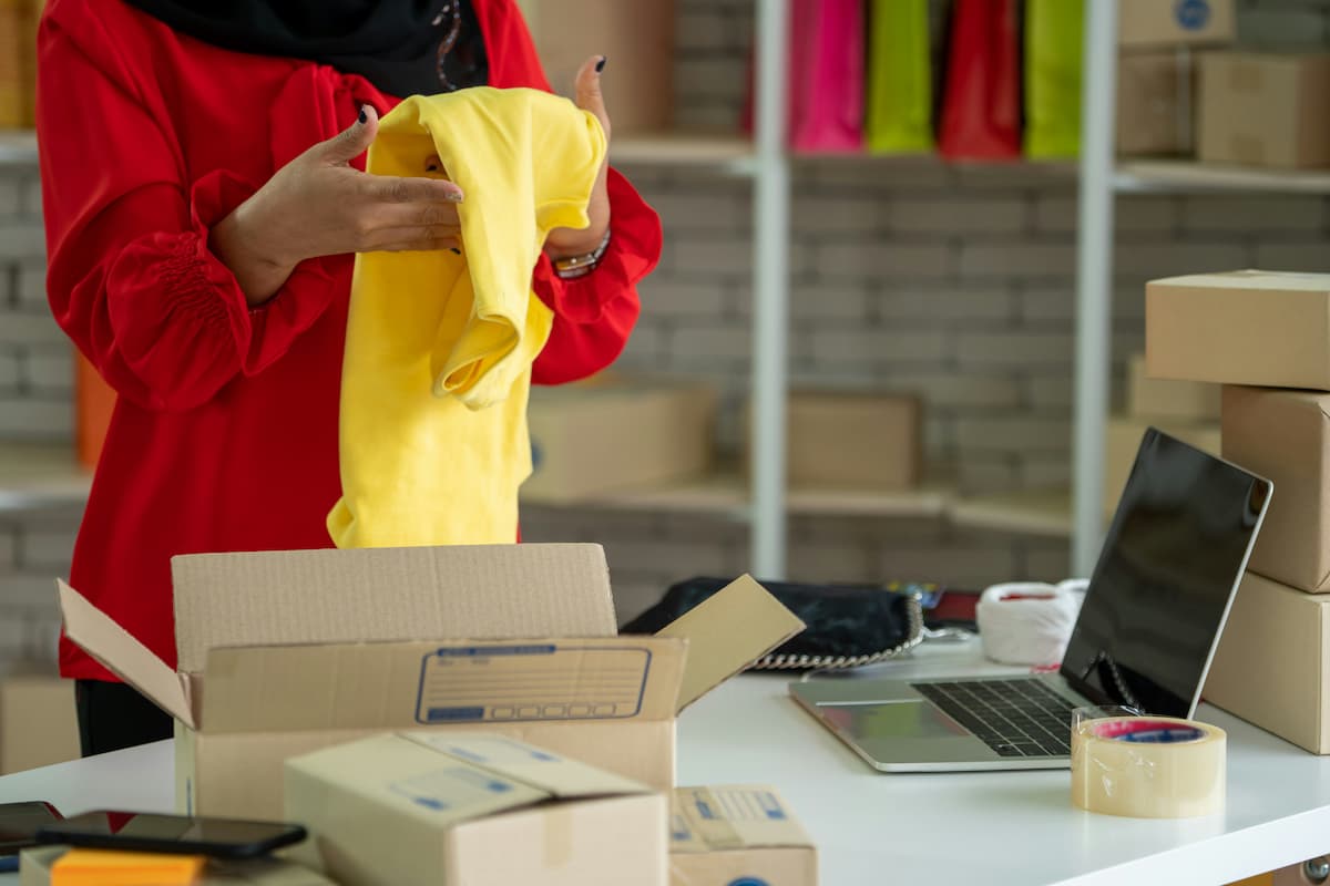 Empreendedora embalando produto em caixa, simbolizando os preparativos para abrir nova loja e expandir seu neg&oacute;cio online.