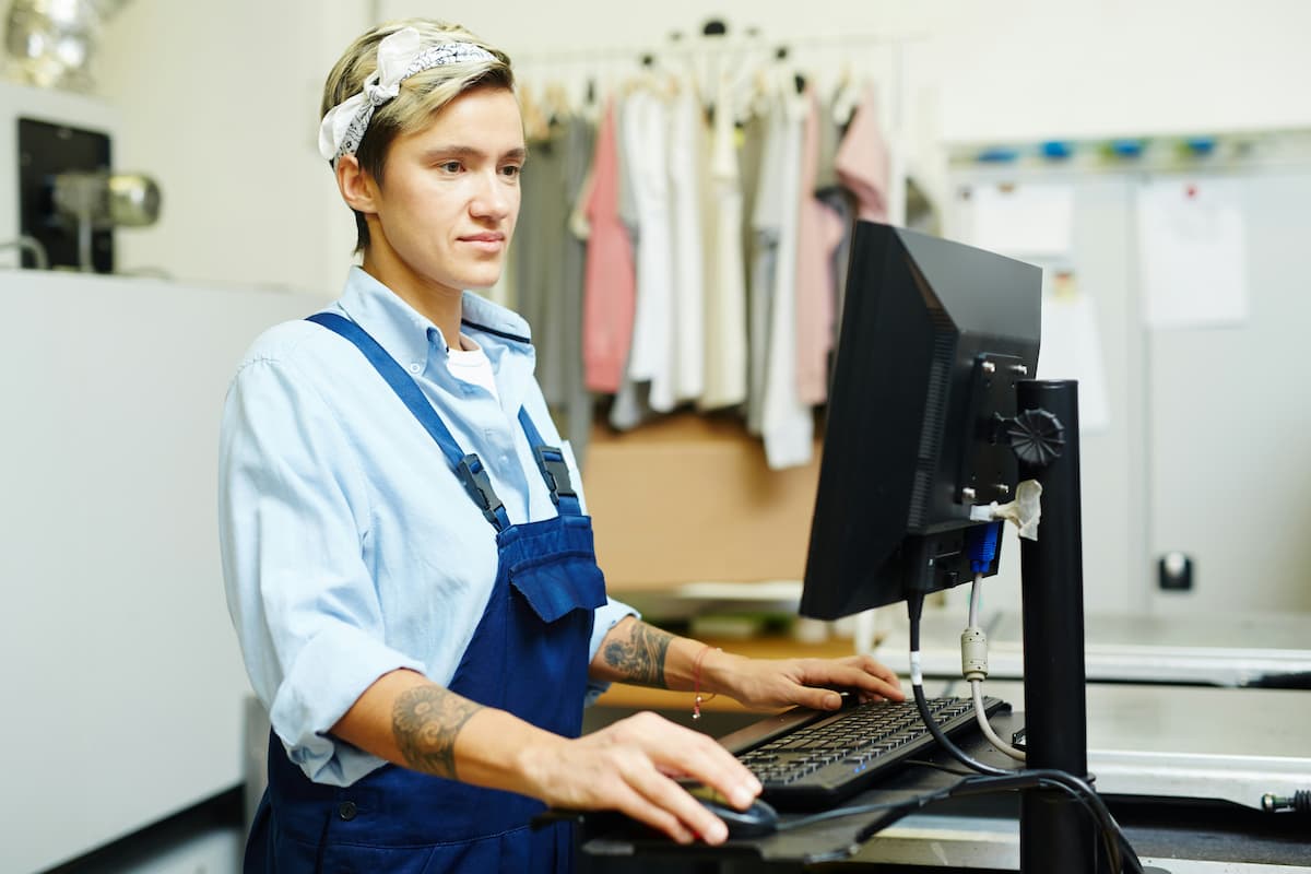 Pessoa trabalhando em frente ao computador em loja de roupas, representando a gestão financeira e a antecipação de recebíveis.