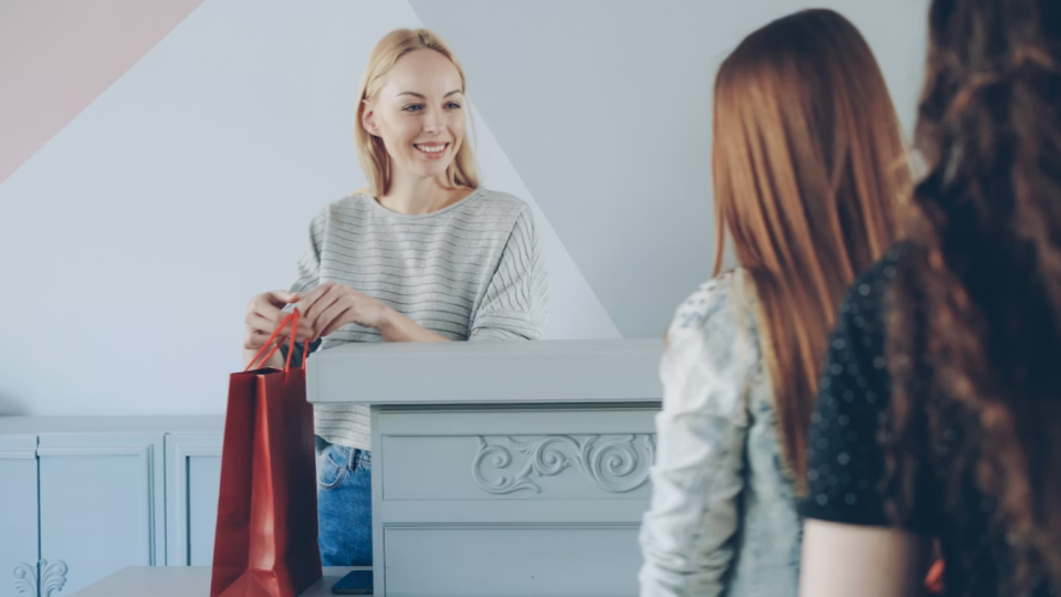 A imagem mostra uma cena de atendimento em um ambiente comercial, possivelmente uma loja.